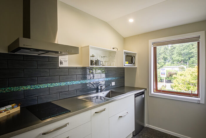 Modern kitchen with white joinery and stainless steel appliances in Red Tussock Motel's Deluxe studio unit.